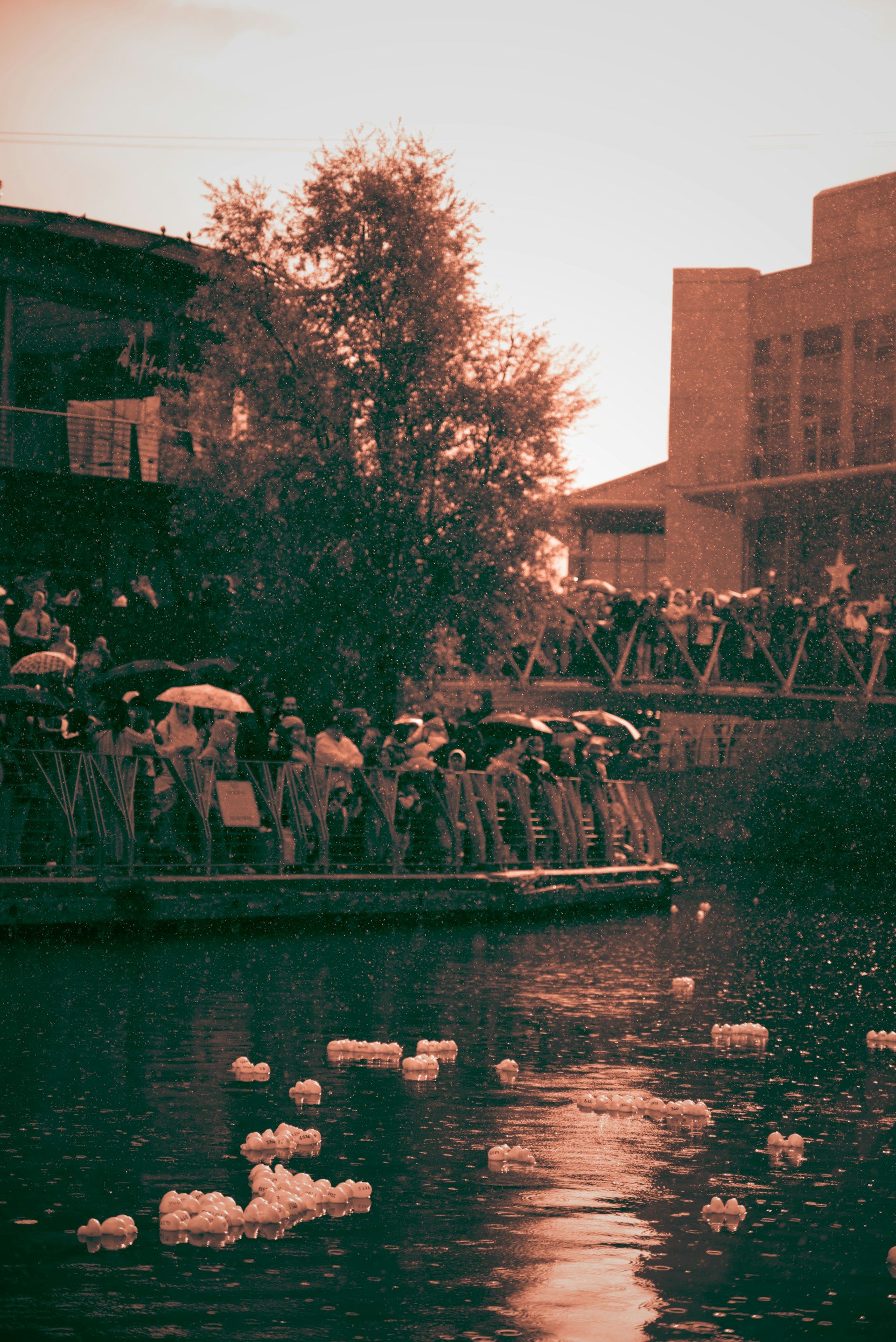People with umbrellas on a boat with floating lanterns.