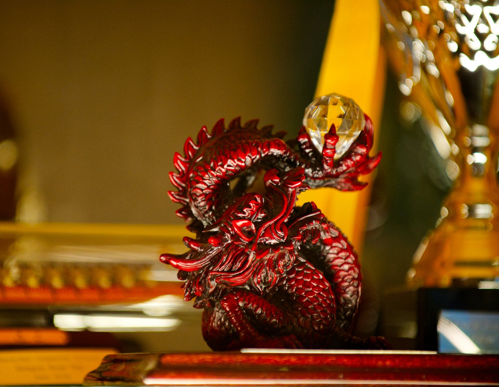 A detailed red dragon figurine with a crystal orb.
